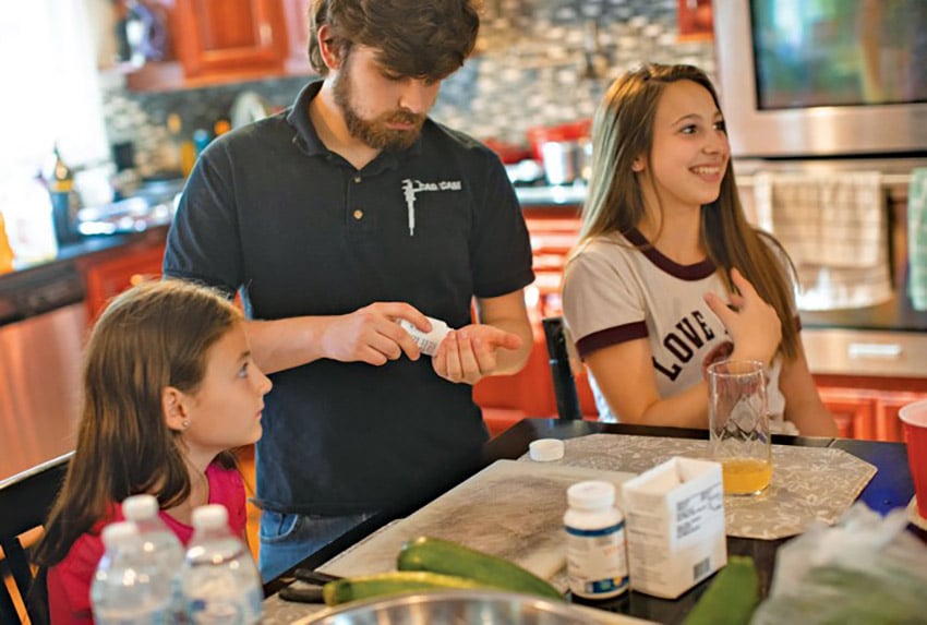 Anthony Parrazzo (center) counts out 11 pills of Kuvan, which he takes every day to help manage his PKU. Lauren Ward (left) and Samantha Parrazzo (right) take a powdered form of the drug.