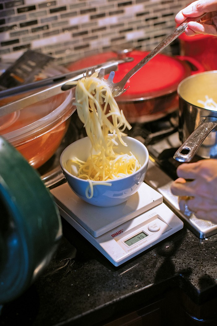 Karen Ward weighs a low-protein pasta made from cornstarch and potato flour for her daughter Lauren so that she can calculate how many grams of phenylalanine it contains.