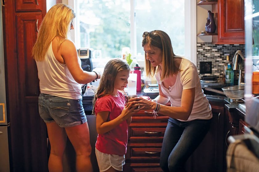 Karen Ward (right) gives her daughter Lauren (middle) her medical formula before dinner. The drink contains the 19 amino acids besides phenylalanine, and many of her calories for the day.